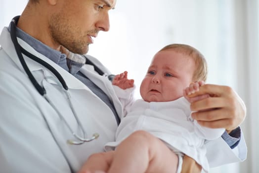 Doctor, pediatrician and crying baby in clinic for medical assessment, support and growth. Sad, scared and sick newborn kid with pediatrics physician for healthcare service, hospital test or wellness.