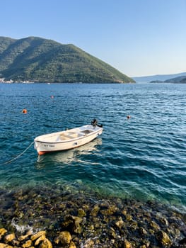White fishing boat moored on the shallows against the backdrop of the mountains. High quality photo