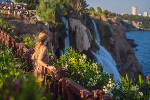 Beautiful woman with long hair on the background of Duden waterfall in Antalya. Famous places of Turkey. Lower Duden Falls drop off a rocky cliff falling from about 40 m into the Mediterranean Sea in amazing water clouds. Tourism and travel destination photo in Antalya, Turkey. Turkiye.