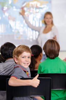 Kid, portrait and thumbs up of student in classroom, elementary school or class. Smile, education and child with hand gesture for like emoji, agreement or learning, success and sign of approval