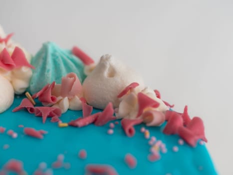studio shot of chocolate frosted blue dripped icing white cup cake, unicorn , meringue and sprinkles on top