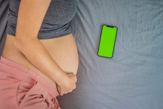 Pregnant girl with a smartphone. The concept of a negative impact on the unborn child in the womb. Violation of the nervous system of the child, reproductive.