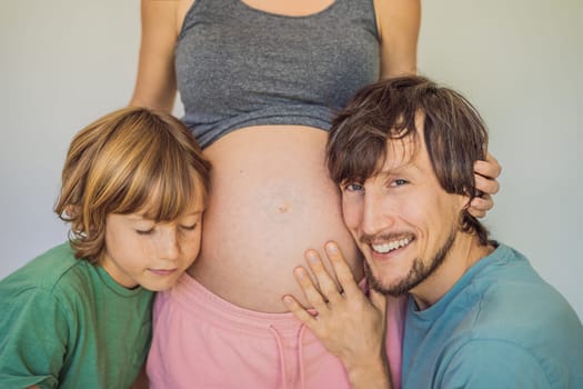 Father and elder son listen to mom's pregnant belly.