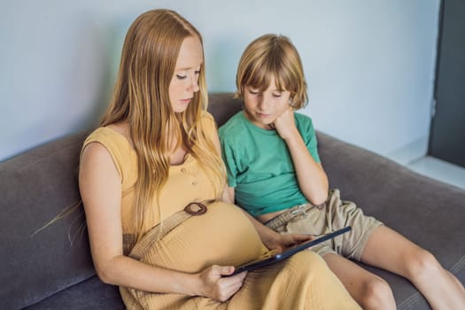 Mom and her son looking on ultrasound image of his unborn baby brother on mothers tablet. Concept of healthcare and family happiness expecting baby.