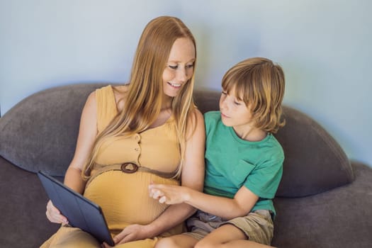 pregnant mom and son look at the tablet. Reading a book or watching a cartoon or making a video call. Look at the photo from the ultrasound.