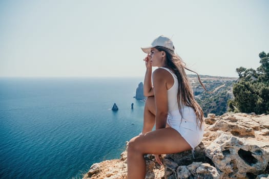 Woman travel sea. Young Happy woman in a long red dress posing on a beach near the sea on background of volcanic rocks, like in Iceland, sharing travel adventure journey