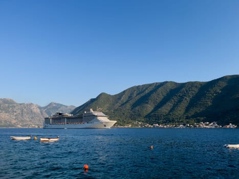 Large cruise liner sails along the Bay of Kotor against the backdrop of green mountains. Montenegro. High quality photo