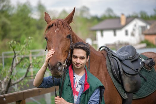 People and animals friendship concept, lifestyle summer outdoor. Young boy during the high mounting walking meets a young horse and communicates with it, wild nature.