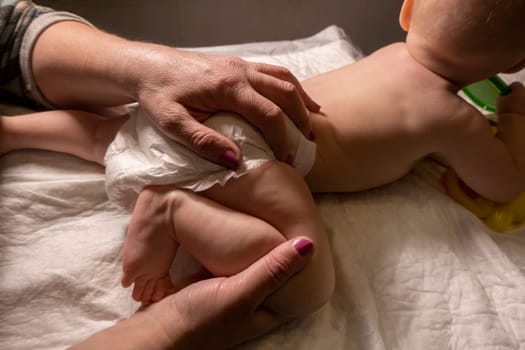 baby massage. The hands of an adult - a mother or a masseur - massage a little girl. Dark background