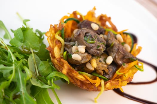 Recipe for poultry giblets in a nest of fried potatoes with rocket and tomato salad. High quality photo