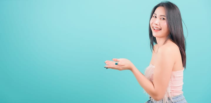 Asian happy portrait beautiful young woman standing her showing holding something with two hands and looking to camera isolated on blue background with copy space for text