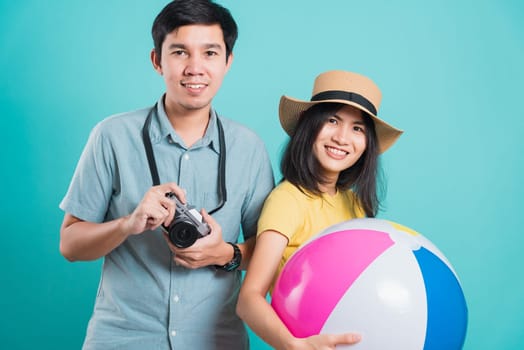 Happy Asian young beautiful woman handsome man couple in summer in holiday travel beach accessories ball and camera isolated on blue background with copy space for text