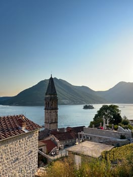 Bell tower of the church of St. Nicholas in Perast against the backdrop of the sea and mountains. Montenegro. High quality photo