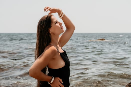 Woman travel sea. Young Happy woman in a long red dress posing on a beach near the sea on background of volcanic rocks, like in Iceland, sharing travel adventure journey