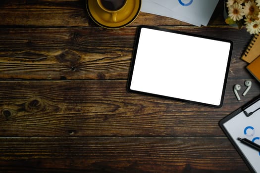 Flat lay, top view of digital tablet with white empty screen, financial document and coffee cup on wooden office desk.