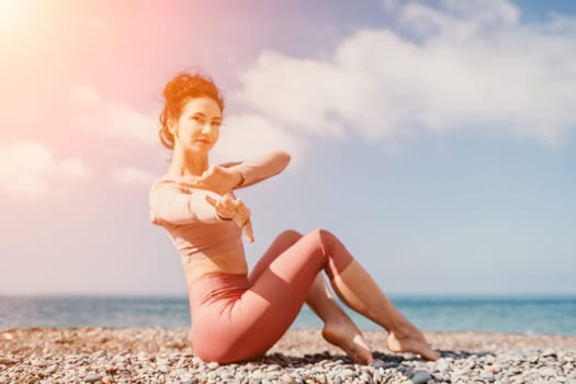 Young woman with long hair in white swimsuit and boho style braclets practicing outdoors on yoga mat by the sea on a sunset. Women's yoga fitness routine. Healthy lifestyle, harmony and meditation