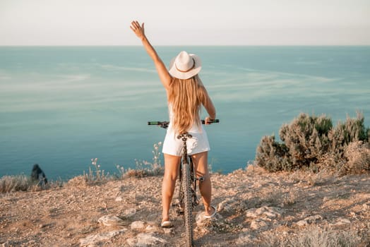 A woman cyclist on a mountain bike looking at the landscape sea. Adventure travel on bike