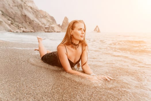 Woman travel sea. Young Happy woman in a long red dress posing on a beach near the sea on background of volcanic rocks, like in Iceland, sharing travel adventure journey