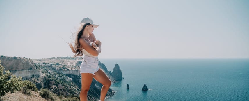 Woman travel sea. Young Happy woman in a long red dress posing on a beach near the sea on background of volcanic rocks, like in Iceland, sharing travel adventure journey