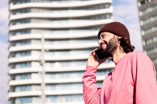 joyful young guy on phone smiling in bright city morning, concept of urban lifestyle and technology of communication, copy space for text