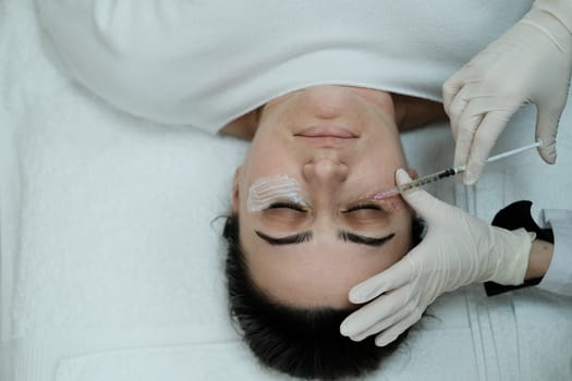 Top view of female patient having eye mesotheraphy applied. Eye mesotherapy procedure. Serum being applied in the undereye area via a syringe.