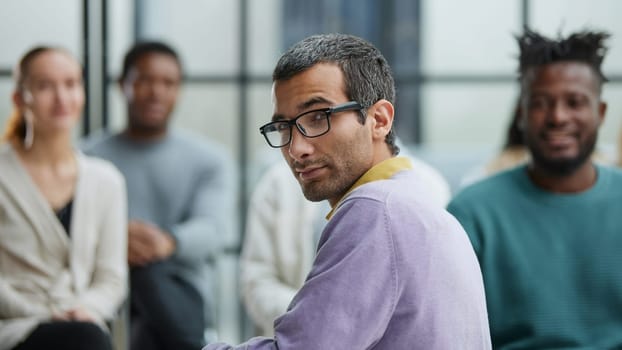 Positive people sitting on a chair, taking part in a team building or therapy session