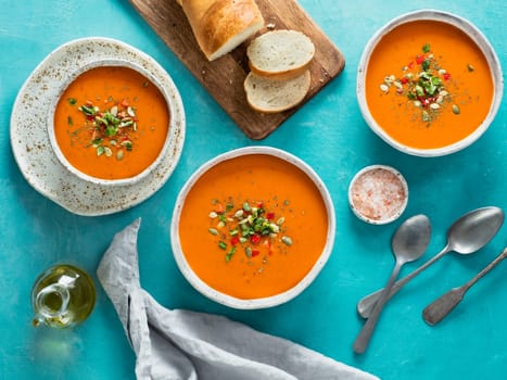 Gaspacho soup on blue tabletop. Three bowls of traditional spanish cold soup puree gaspacho or gazpacho on bright blue background. Top view or flat lay.