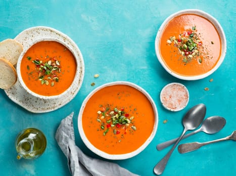Gaspacho soup on blue tabletop. Three bowls of traditional spanish cold soup puree gaspacho or gazpacho on bright blue background with copy space for text. Top view or flat lay.