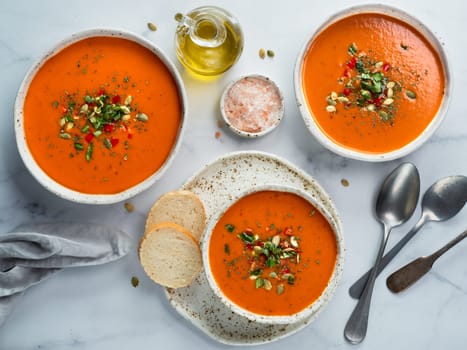 Gaspacho soup on white marble tabletop. Three bowls of traditional spanish cold soup puree gaspacho or gazpacho on light gray or white marble background. Top view or flat lay.