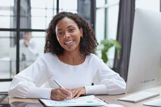woman sitting at desktop with laptop noting down important information