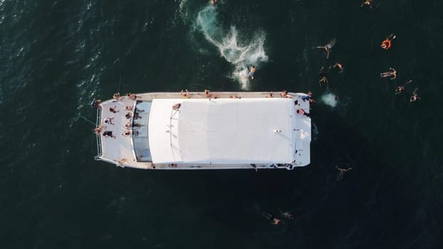 aerial view of a yacht in the ocean and floating people. High quality photo