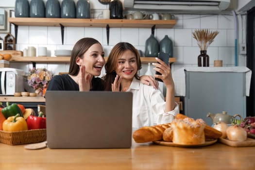 Happy teenage girls making or video calling while resting in the kitchen.