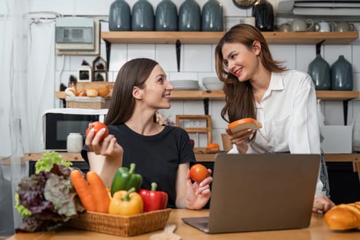 Two beautiful woman friends enjoy breakfast in kitchen drinking coffee. Two best friends LGBTQ relation partner home cooking. Two woman together love friendship.