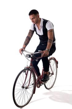 Portrait of young tattooed man in elegant clothes riding a bicycle. Studio shot. Full body shot