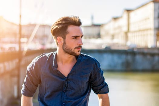 One handsome young man in urban setting in European city, Turin in Italy by the river Po