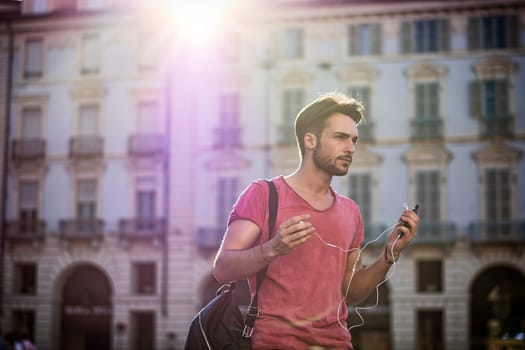 Attractive young man walking in the middle of city street looking straight crossing in front of cars