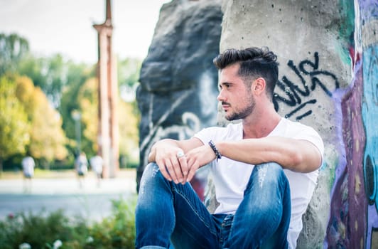 Handsome fit man in white t-shirt outdoor in city setting, looking away