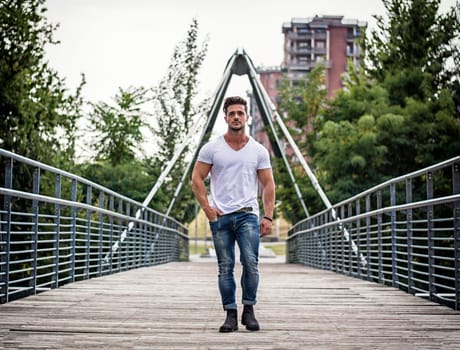 Handsome fit man in white t-shirt outdoor in city setting, looking away