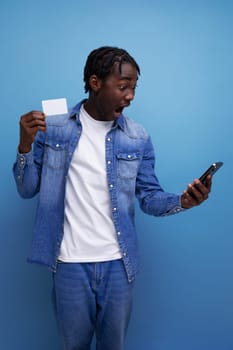 stylish american man with black dreadlocks holding money card mockup and smartphone.