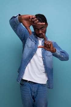 close-up portrait of a young African guy with dreadlocks in a denim jacket taking a photo.