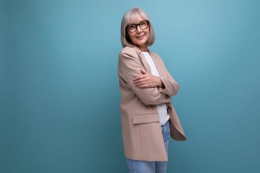 successful middle-aged woman grandmother with gray hair in a jacket on a bright background with copy space.