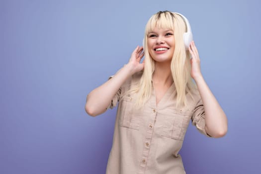 charming blonde uses phone app to listen to music on headphones.