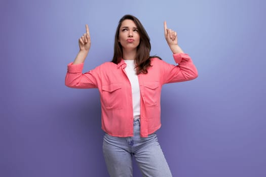 focused black haired lady in casual style pointing thumb up at mockup space on studio background.