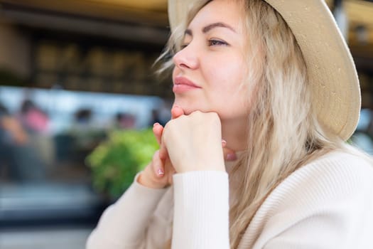 Close-up portrait of a pensive woman looking away, posing against the backdrop of nature. Beautiful woman with a pensive expression is resting outdoors in the park.