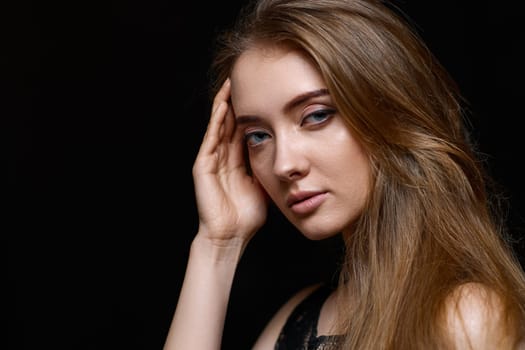 gorgeous brunette woman with long hair in black dress on black background. copy space