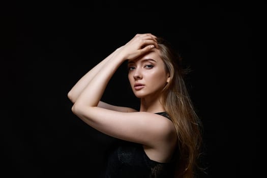 gorgeous brunette woman with long hair in black dress on black background. copy space