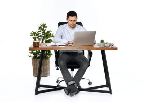 young man using laptop computer for online work at table on white background