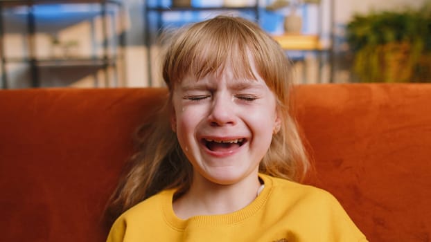 Close-up portrait of upset punished child little girl kid crying with tears flowing down on cheeks at home. Quarrel, fear abuse, bullying, education test exam fail at school. Family violence concept