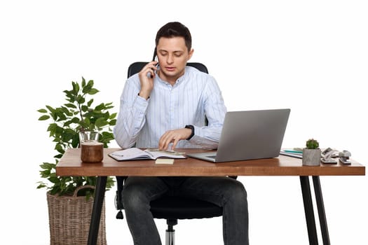 Successful happy businessman working with laptop and having phone conversation with client