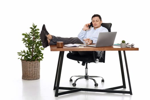 Successful freelancer man working with laptop and having phone conversation with client